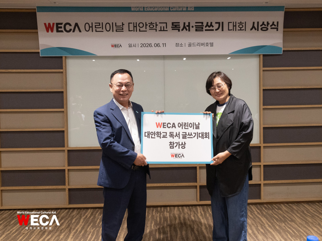 인천 대안학교 독서·글쓰기 대회를 기념하여 무대 위에서 판넬을 함께 들고 기념 촬영을 진행 중인 세계교육문화원 방정환 이사장과 대안학교 대표 교장