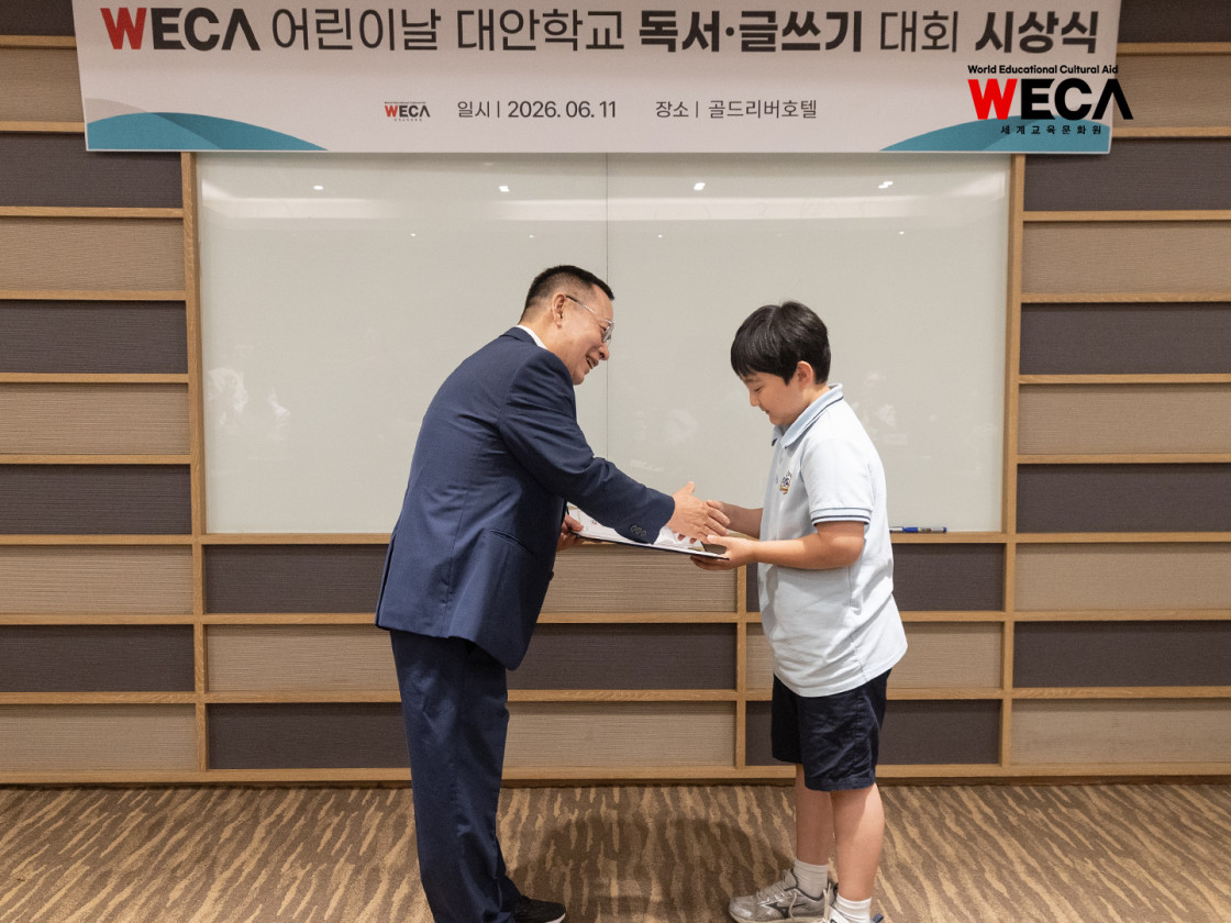독서·글쓰기 대회 시상식 단상 위에서 장려상을 수상한 대안학교 아이에게 다정하게 상장을 수여하고 있는 세계교육문화원 방정환 이사장