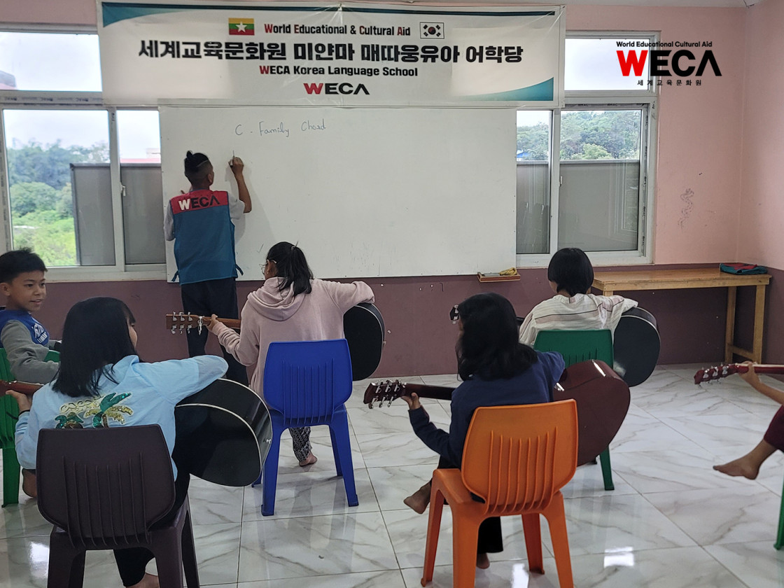 미얀마 WECA어학당에서 아이들이 선생님의 지도를 받으며 기타연주를 배우고 있는 모습