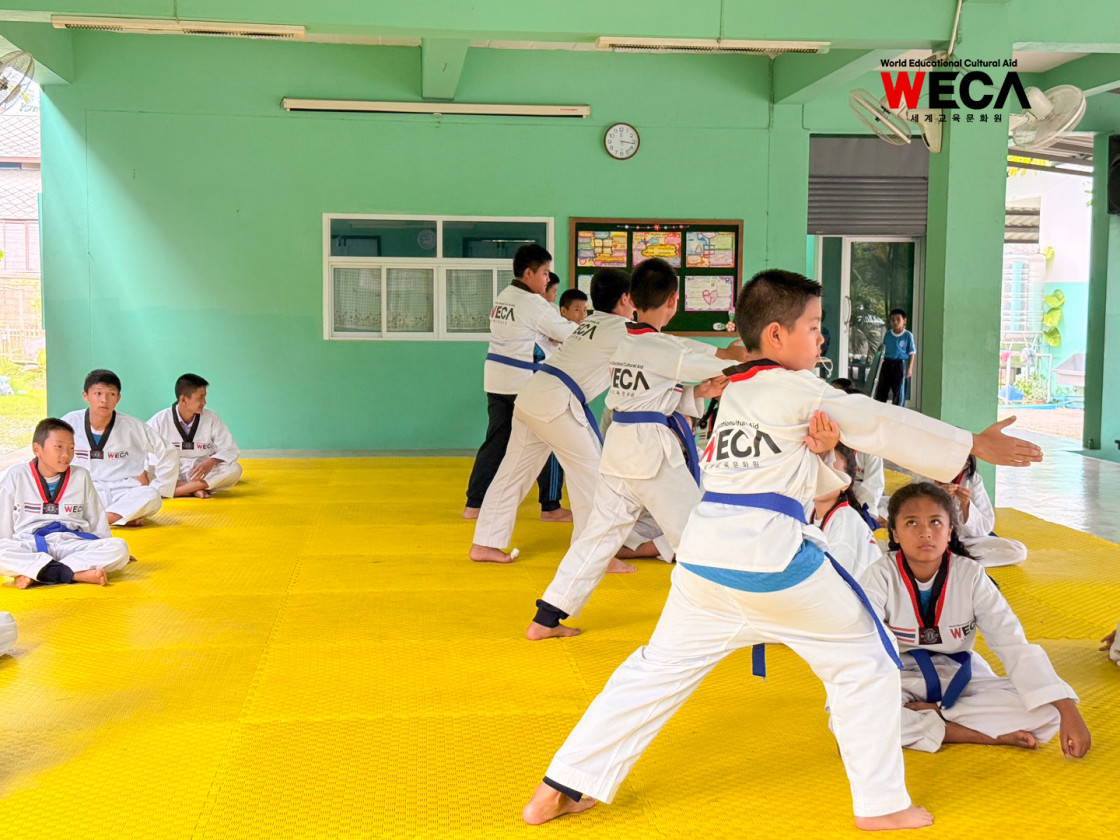 세계교육문화원 WECA 태국 치앙마이 반동초등학교 6학년 학생들이 도복을 입고 태극 4장 품새 동작을 연습하는 모습