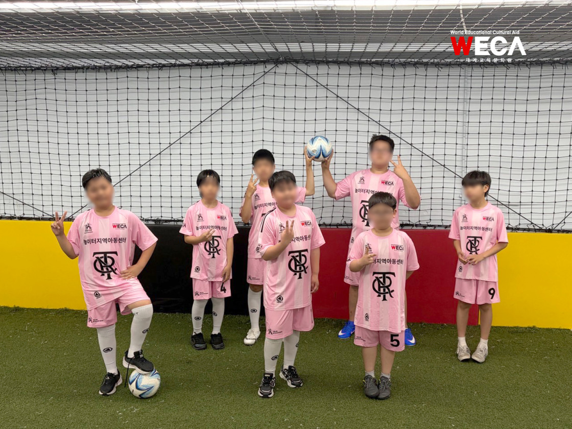 위카 축구 유니폼을 맞춰 입고 골대 앞에서 사진을 찍는 아이들