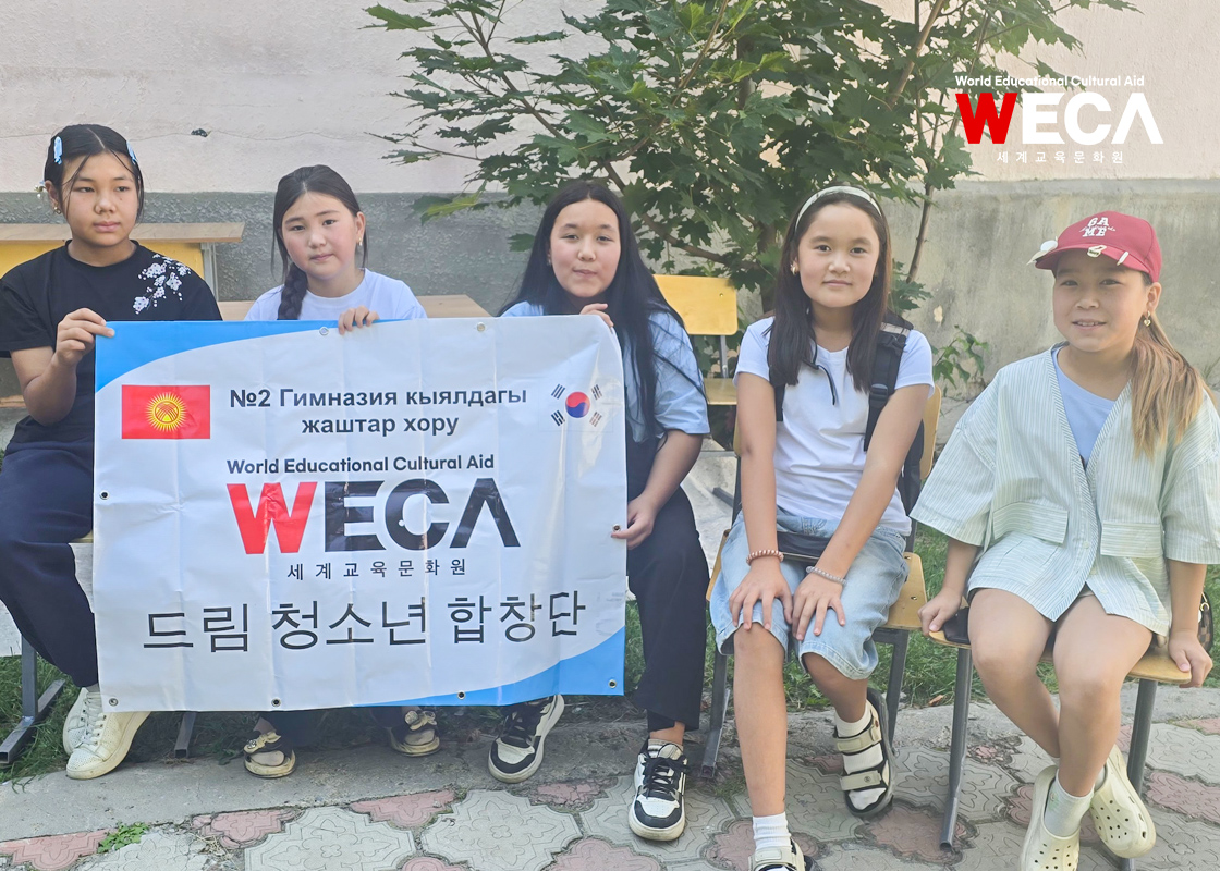 WECA 드림 청소년 합창단 현수막을 들고 웃으며 카메라를 쳐다보는 아이들