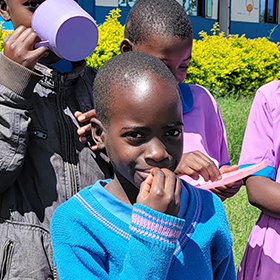 Ugandan children eating free meals with their friends